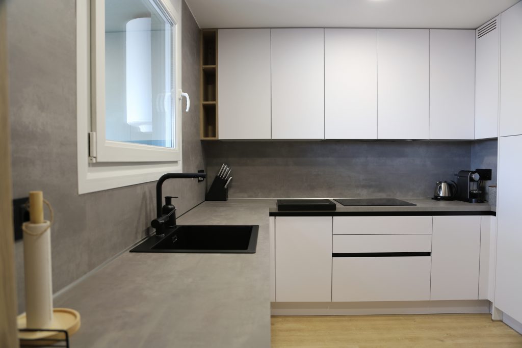 Cocina con muebles blancos y encimera gris.