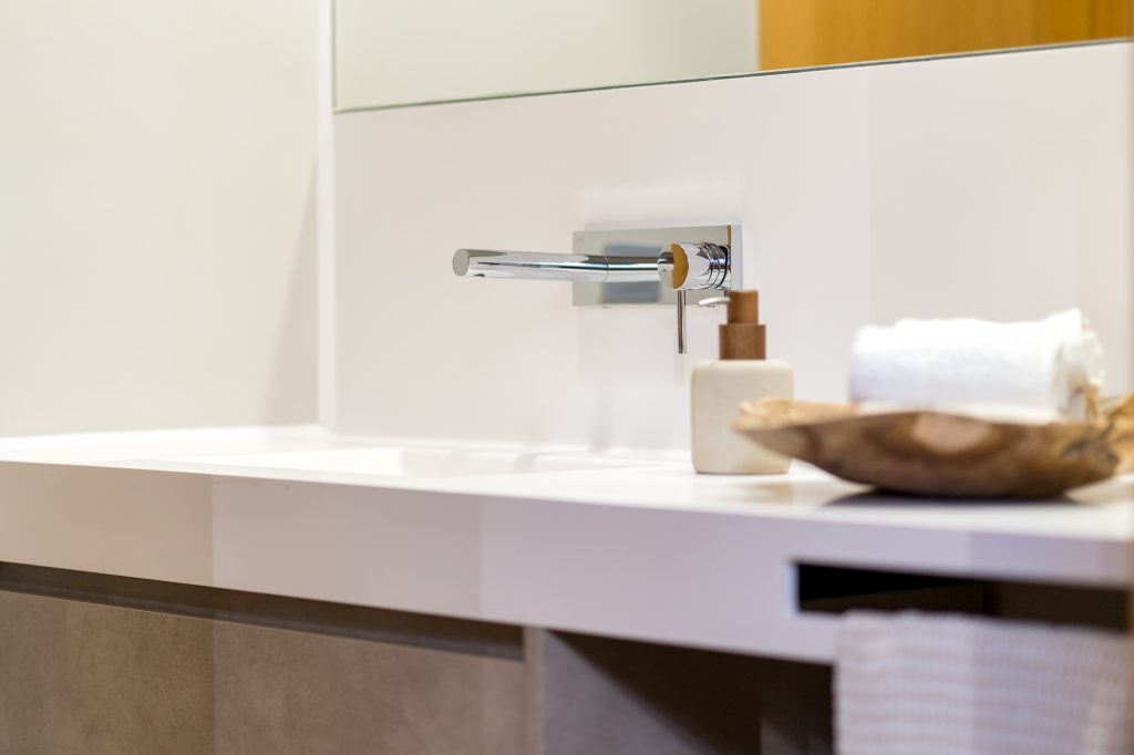 Lavabo de Kyrya con encimera blanca y mueble modular gris.